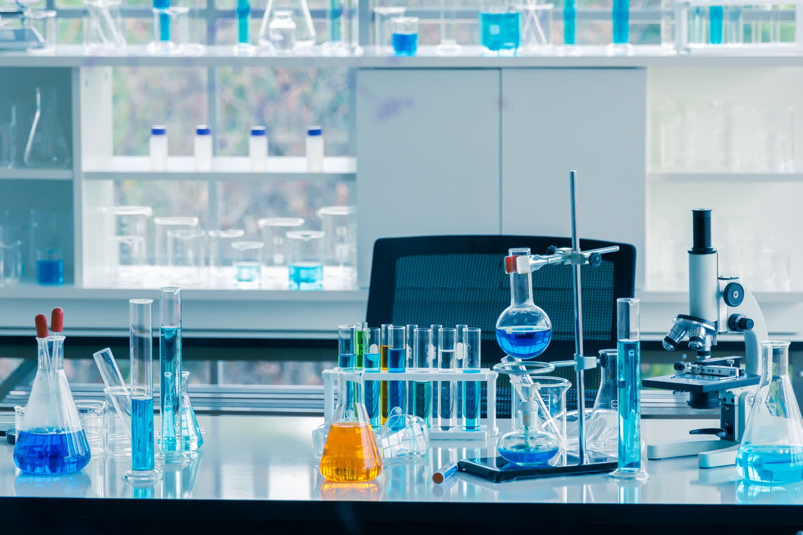 Scientific glassware, test tube rack and microscope on a laboratory bench